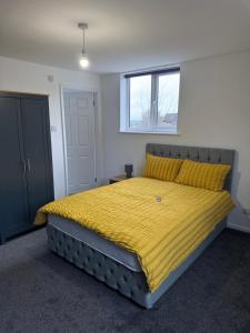 a bedroom with a large bed with a yellow blanket at Modern room in west hallam in Derby