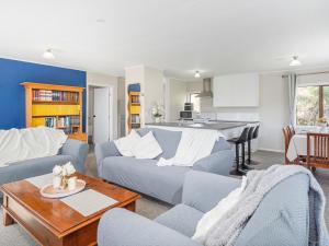 a living room with a couch and a table at Onemana Magic - Onemana Holiday Home in Opoutere