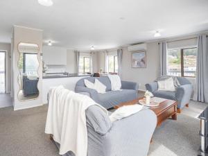 a living room with two couches and a table at Onemana Magic - Onemana Holiday Home in Opoutere