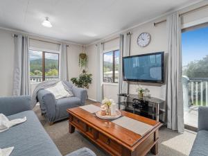 a living room with a tv and a table at Onemana Magic - Onemana Holiday Home in Opoutere