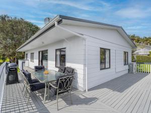 a white house with a table and chairs on a deck at Onemana Magic - Onemana Holiday Home in Opoutere
