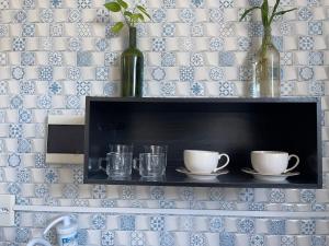 une étagère avec deux tasses et une bouteille sur un mur dans l'établissement Studio-style apartment in a family environment, à Salvador 16 autres photos