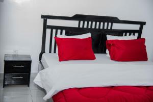 a bedroom with a white bed with red pillows at Kibagabaga Homes Stay in Kigali