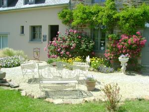 a garden with benches and flowers in front of a house at La Porte Ouverte in Saint-Denoual
