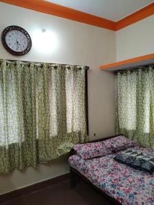 a bedroom with a bed and a clock on the wall at Roopa Studio in Mysore
