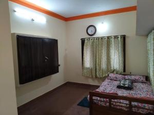 a bedroom with a bed and a clock on the wall at Roopa Studio in Mysore +2 photos