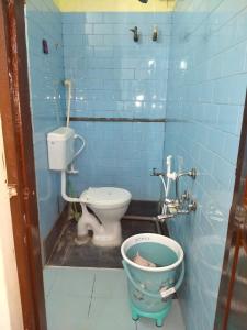 a blue tiled bathroom with a toilet and a bucket at Roopa Studio in Mysore