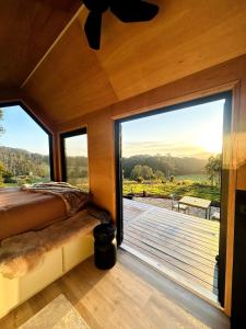 Cette chambre comprend un lit et une grande fenêtre. dans l'établissement SkyDreamer - Tiny Home at Jamberoo Mountain Farm, à Tongarra
