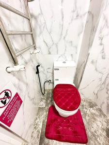 a bathroom with a red toilet with a red mat at Comfortable Apartments in Tashkent