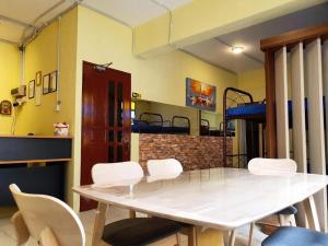 Una mesa en una habitación con sillas blancas y literas. en Hotel O Arriva Travellers, en Kuching