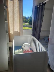 Una cuna blanca con un animal de peluche. en Maison BRIALI avec Jacuzzi espace détente, en Aubignan