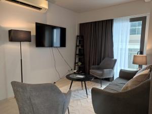 a living room with a couch and chairs and a tv at Tambuli Seaside Resort 16G - Lapu Lapu in Maribago