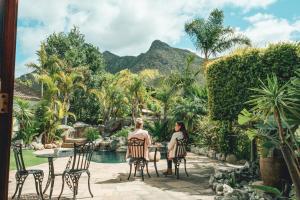 two women sitting at a table in front of a pool at Villa Chad Luxury Guesthouse in Kleinmond