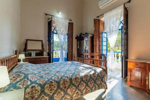 Lov Heritage Goa في Chinchinim: غرفة نوم بسرير وخزانة ونوافذ