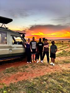 a group of people standing in front of a van at Serian safaris and travel tours in Sekenani