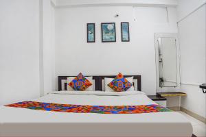 ein Schlafzimmer mit einem großen weißen Bett mit bunten Kissen in der Unterkunft FabHotel The Vinayak in Bhopal