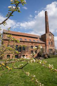 an old brick building with a chimney and a flowering tree at LOFT in Ribbeck in Nauen