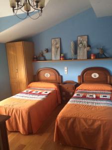 2 camas en una habitación con paredes azules en Hostal Monica en Cilleruelo de Bezana