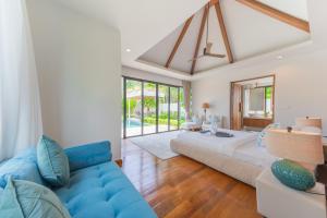 - un salon avec un grand lit et un canapé bleu dans l'établissement BangTao Luxury 5 Bedroom 1200sqm Modern Bali Style Holiday Villa Quiet and Private Large Private Pool Large Garden, à Ban Pak Lak