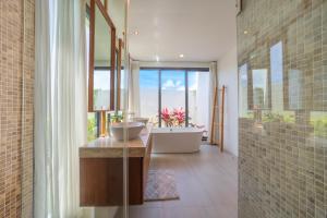une salle de bain avec une baignoire et un lavabo et une baignoire dans l'établissement BangTao Luxury 5 Bedroom 1200sqm Modern Bali Style Holiday Villa Quiet and Private Large Private Pool Large Garden, à Ban Pak Lak