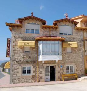 un edificio in pietra con una caffetteria sul lato di Hostal Monica a Cilleruelo de Bezana