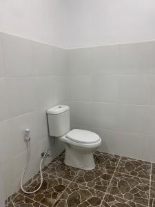 a bathroom with a white toilet in a room at Batur Jemsokin Logement in Bangli