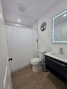 a white bathroom with a toilet and a sink at Delray Beach Sunshine - 5 minutes from beach! in Delray Beach