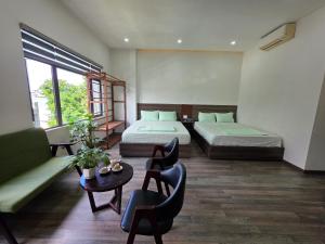 a room with two beds and a couch and a table at Rami Xanh Stay in Danang