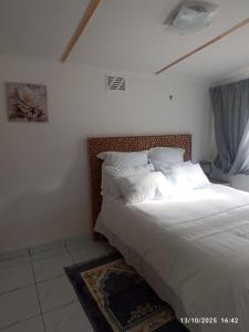 een slaapkamer met een bed met witte lakens en kussens bij Chez Matli in Tiervlei