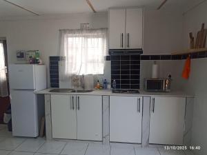 een keuken met witte kasten en een witte koelkast bij Chez Matli in Tiervlei