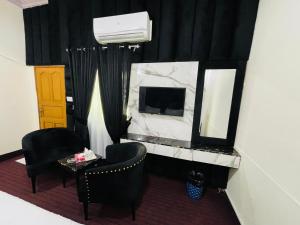une pièce avec une télévision, deux chaises et un miroir dans l'établissement Clift Royal In, à Islamabad