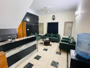 un grand salon avec des canapés verts et un aquarium dans l'établissement Clift Royal In, à Islamabad