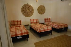 a room with two beds and two ottomans at Al Hudu Mountain House - Jebel Shams in Al Ḩayl