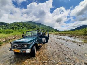 a blue truck driving down a dirt road at The Corbett Rajae Homestay in Badīyārgaon