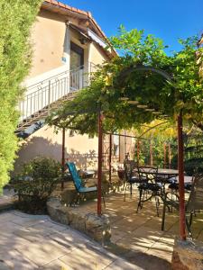 un patio con tavolo, sedie e alberi di - - - - -Les Colombages - - - - Chambre d'hôtes-Gîte- Classement Gîte 3 étoiles a Mirepoix