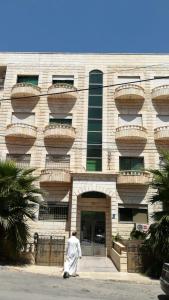 a man walking in front of a building at الرائد للشقق المفروشة in Amman