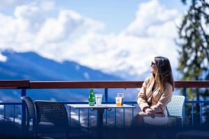 a woman sitting at a table with a drink at Villages Clubs du Soleil - ARC 1800 in Arc 1800