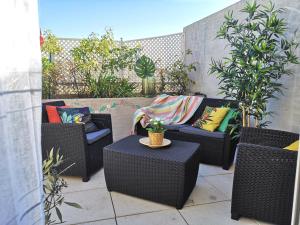 un patio con sillas de mimbre y una mesa con almohadas de colores. en Superbe Appartement 2 Chambres, en La Ciotat