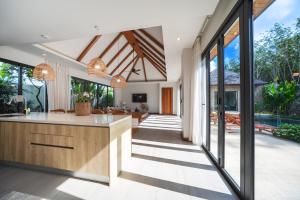 une cuisine ouverte et un salon avec de grandes fenêtres dans l'établissement BangTao Luxury 5 Bedroom 1200sqm Modern Bali Style Holiday Villa Quiet and Private Large Private Pool Large Garden, à Ban Pak Lak