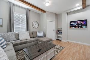 a living room with a couch and a clock on the wall at Stockyards- 4min Pet Friendly 3BR Luxe Gem in Fort Worth