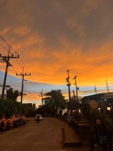 un coucher de soleil avec une voiture roulant dans une rue dans l'établissement Happy Beach Hostel, à Ko Lanta Yai