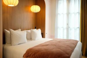 パリにあるHôtel Casimirのベッドルーム1室(白い枕のベッド1台、窓付)