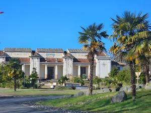 a building with palm trees in front of a road at Villa Milady in Salies-du-Salat