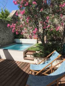 a swimming pool with two lounge chairs and flowers at Cozy 2 bedroom house - 4 people in Bourg-Saint-Andéol
