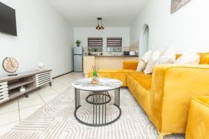 Una sala de estar con un sofá amarillo y una mesa. en Sandton Luxury Apartment, 82 Via Arrezio, en Johannesburgo