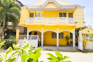 ein gelbes Haus mit einem weißen Zaun davor in der Unterkunft Iloilo Transient Rooms in Iloilo City