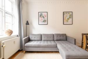 a gray couch in a living room with a window at Homely 5 Person Apartment in Amager in Copenhagen +42 photos