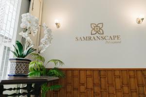 a company logo on a wall with a table and plants at Samranscape in Bangkok