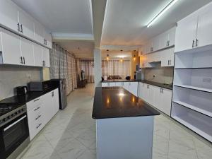 a kitchen with white cabinets and a black counter top at Pofu Stay Eldoret in Eldoret