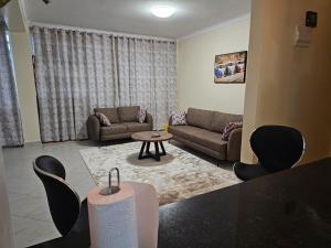 a living room with a couch and a table and chairs at Pofu Stay Eldoret in Eldoret